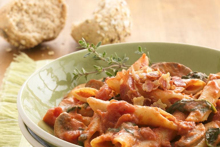 Bowl of pasta with a chunky tomato sauce and garnish.