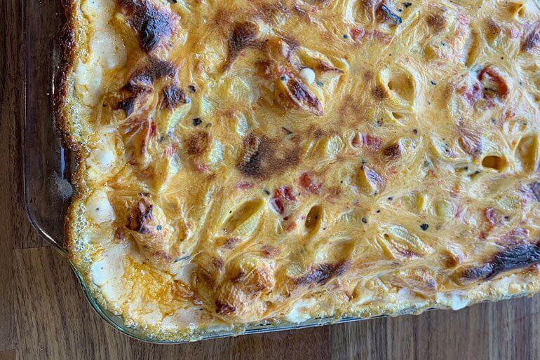 Baked mac and cheese recipe with fire roasted tomatoes served in a glass casserole dish.